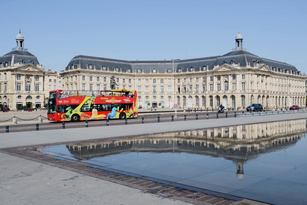 The Visiotour hop-on hop-off bus reflected in Bordeaux's Water Mirror, Place de la Bourse